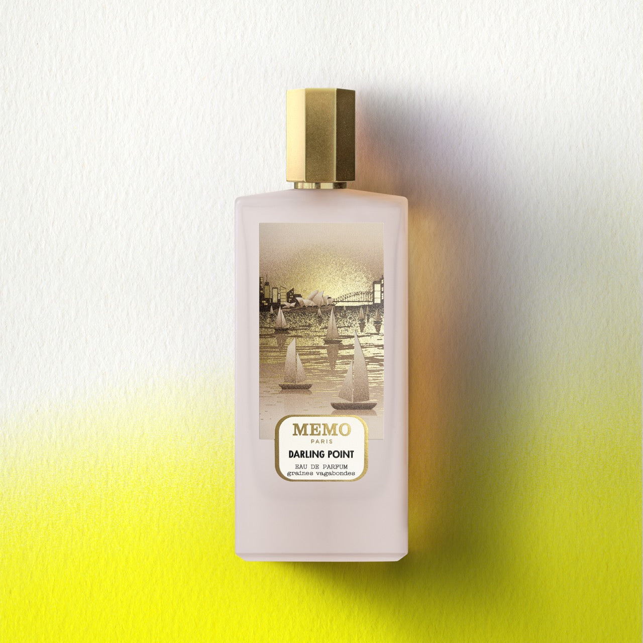 A pale pink rectangular perfume bottle with a gold cap and illustrated sailboats labeled memo paris darling point unprecedented australian encounter